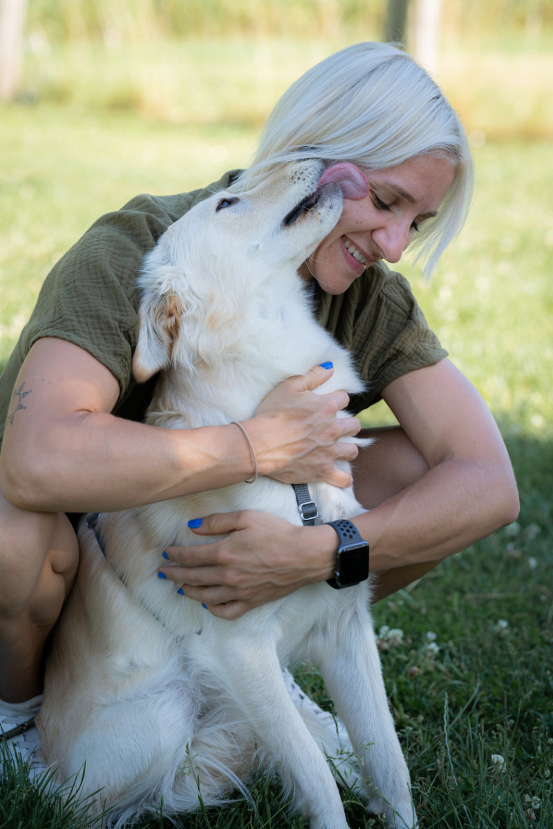 Vertrauensvolle Mensch-Hund-Beziehung: Eine glückliche Teilnehmerin umarmt ihren Hund auf einer Wiese bei der Hundeschule Alfeld.